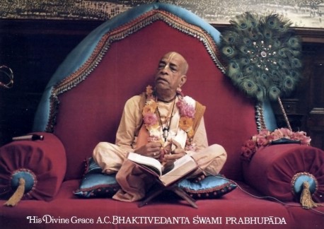 Srila Prabhupada sitting on red Vyasassana playing kartals, 1973