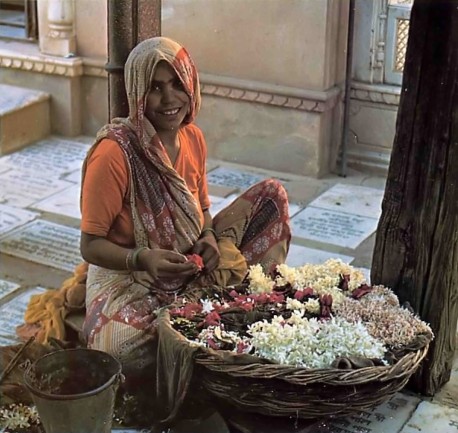 Indian Lady making flower garland to offer to Krishna. Vrindavan, India, 1975.