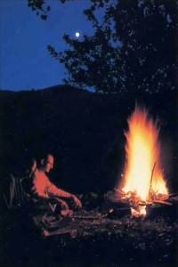 A devotee reads Bhagavad-glta by an evening fire.  France - 1977
