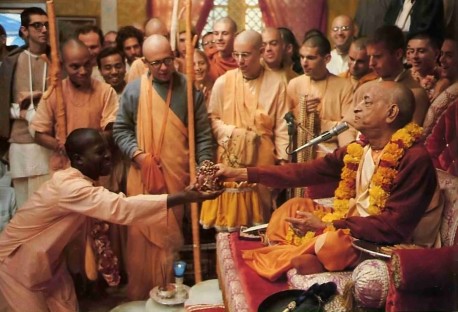 His Divine Grace A. C. Bhaktivedanta Swami Prabhupada hands a new disciple the beads upon which he will chant the Hare Krishna maha-mantra. 1977
