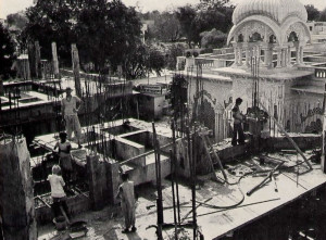 Support beams rise from the newly laid second story of the memorial shrine for Srila Prabhupada in Vrndavana, India. The dome of the Krsna-Balariima temple appears at upper right.