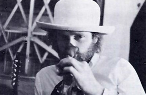Mike Love sniffs at a rose as he listens to the conversation.