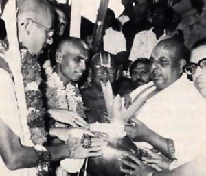 Sri Rangam temple leaders greet the ISKCON pada-yatra with a traditional purna-kumbha reception-leaves and flowers in a pot. From left to right: pada-yatra leadersJayadvaita Swami and Lokanatha Swami; Sri Thirumalai Iyengar, head of the temple priests; Sri N. Rangaraja Bhattar, member of the temple advisory committee, formerly chief priest for forty years; and Dr. Gopinatha Rao, the temple's chief administrator.