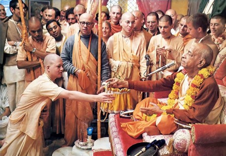 Srila Prabhupada hands sanctified beads to a new initiate. 1975.