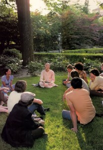 Jayadvaita dasa preaches to a group of students sitting on grass at a US college campus. 1976.