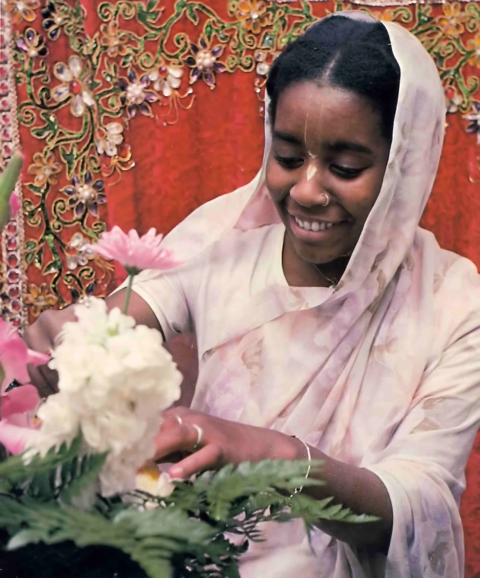 ISKCON devotee makes flower arrangements for offering to the Deities at Hare Krishna Temple. 1976.
