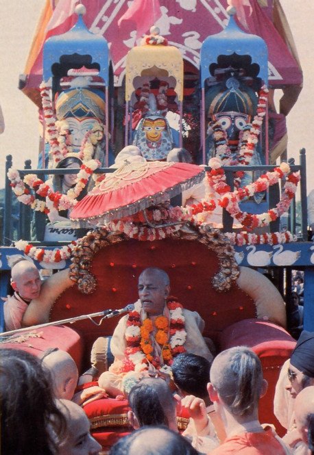 In London in 1972, His Divine Grace A. C. Bhaktivedanta Swami Prabhupada addresses a crowd of devotees and festival-goers at the Festival of the Chariots (see article). Standing majestically above Srila Prabhupada on the towering Ratha-yatra cart are the worship able deity forms of Lord Balarama (Krsna's brother), Srimati Subhadra (Krsna's sister), and Lord Jagannatha (Krsna in His form as the "Lord of the Universe").